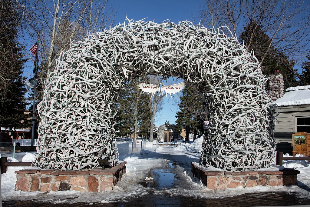 An elk-antler arch on the Jackson Town Square in winter, the Jackson Hole, WY sign hanging beneath it